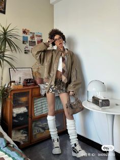 Woman with curly hair and glasses wearing a leather jacket and mini skirt indoors