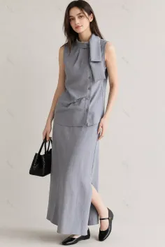Woman in a gray sleeveless top and long skirt holding a black handbag