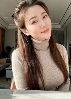 Woman with long hair wearing a turtleneck sweater indoors with soft lighting