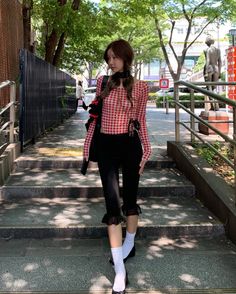 Woman in a red gingham top and black pants walking down outdoor stairs
