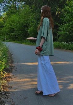 Woman with long hair in an oversized t-shirt and wide leg pants standing barefoot on a road