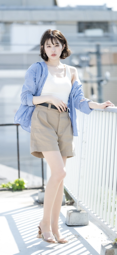 Woman with short hair wearing a striped shirt and khaki shorts outdoors