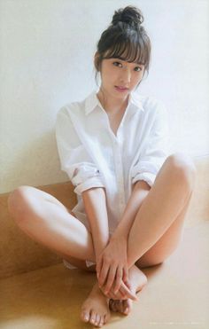 Woman in a white shirt with a messy bun sitting on the floor