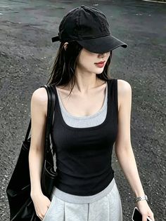 Woman in a black baseball cap and tank top with a shoulder bag outdoors