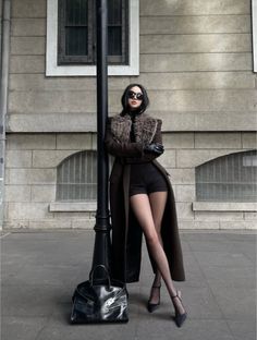 Woman in a long coat with a fur collar and black shorts on a street