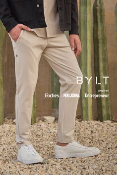 Person in beige pants and white sneakers standing on gravel with cacti in the background