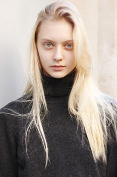 Young woman with long blonde hair wearing a dark turtleneck sweater