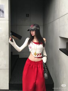 Woman in a crop top and red pants taking a selfie indoors