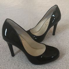 Pair of black patent leather high heels on a light-colored carpet