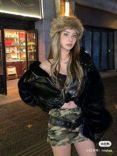Woman in a fur hat and camouflage skirt with an exposed midriff at night