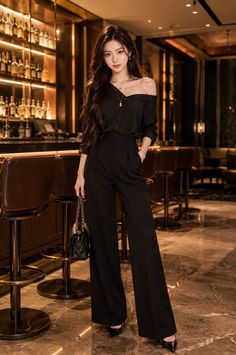 Woman in a black off-shoulder top and wide-leg pants standing in a bar
