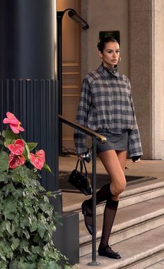 Woman in a plaid jacket and mini skirt walking down outdoor stairs