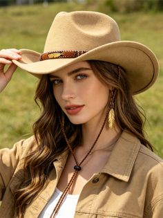 Woman in a cowboy hat and denim jacket with feather earrings outdoors