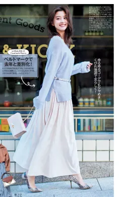 Woman in a light blue sweater and long skirt walking on a street