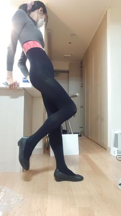 Person in black leggings and a grey long sleeve shirt with a face mask indoors