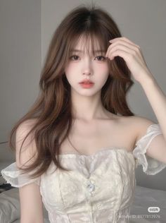 Woman with long brown hair wearing an off-shoulder lace top indoors
