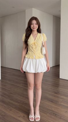 Woman in a yellow top and white bubble skirt standing indoors