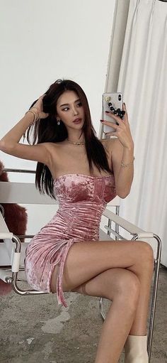 Woman in a pink velvet strapless dress taking a mirror selfie