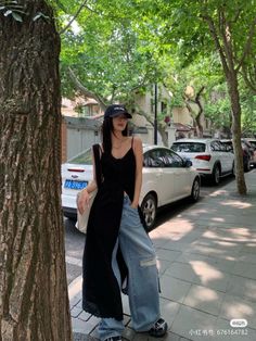 Woman in a black top and wide leg jeans on a tree-lined street