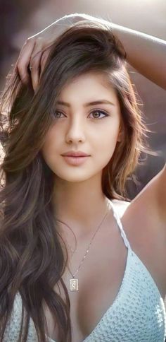 Woman with long brown hair wearing a white top and necklace