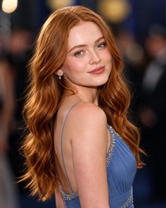 Woman with long red hair in a blue dress looking over her shoulder