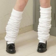 Legs wearing white leg warmers and black shoes indoors
