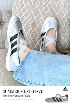 Person wearing light wash jeans and grey sneakers with black stripes on a patterned couch