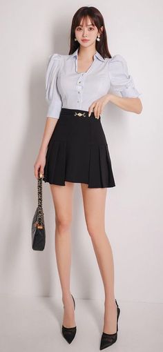 Woman in a white blouse and black pleated skirt holding a handbag