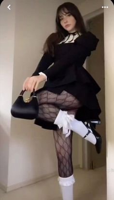 Woman in a black dress and patterned tights holding a small black handbag
