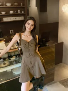 Woman in a brown dress and black boots smiling indoors