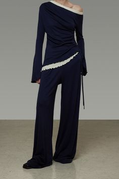 Person in a navy blue off-shoulder top and wide-leg pants with ruffle trim