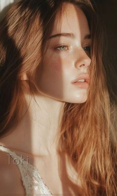 Woman with long red hair and freckles in soft, warm lighting