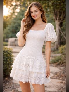 Woman in a white dress with eyelet lace details outdoors at golden hour