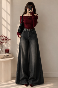 Woman in a maroon off-shoulder top and wide-leg jeans holding a phone