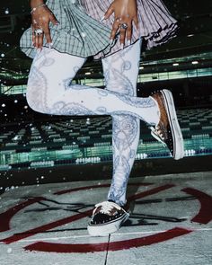 Person in a plaid skirt and patterned tights with sneakers outdoors at night