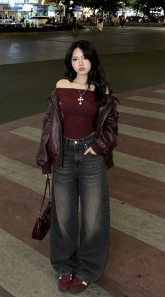 Woman in an off-shoulder top, leather jacket, and baggy jeans on a street at night