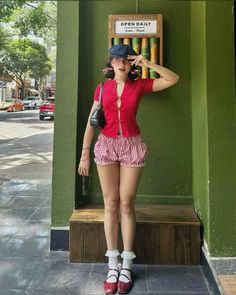 Woman in a red top and gingham shorts posing outdoors