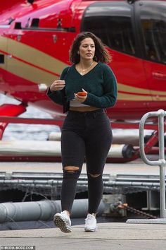 Woman in a cropped sweater and ripped jeans walking outdoors