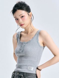 Woman in a grey tank top with an updo and pink blush in a studio