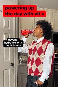 Person with curly hair drinking from a bottle in a kitchen