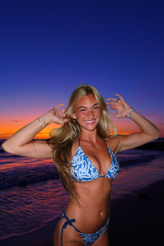 Woman in a blue bikini on a beach at sunset