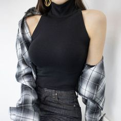 Woman in a black turtleneck and plaid shirt with dark wash jeans