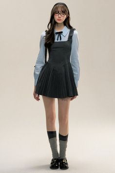 Woman in a pleated dress over a blue shirt, glasses, and a headband