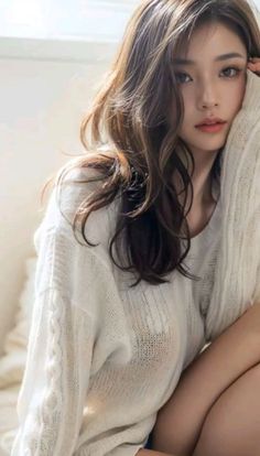 Woman with long brown hair wearing a sheer white sweater indoors