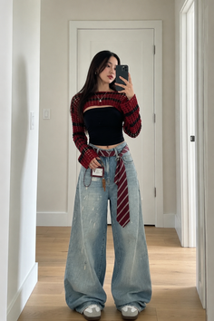 Woman in a cropped sweater and wide leg jeans taking a mirror selfie