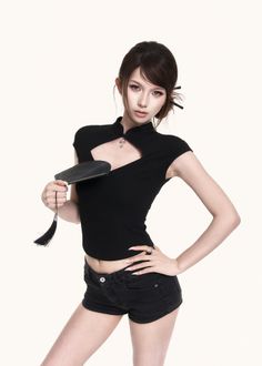 Woman in a black top and shorts holding a fan in a studio