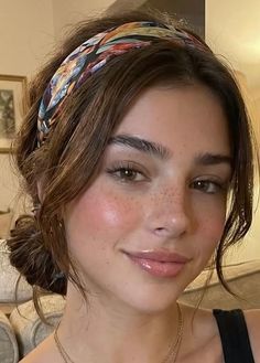 Woman with brown hair, a colorful headband, and freckles smiling at the camera