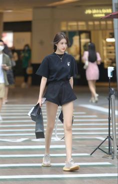 Woman in a black t-shirt and shorts walking on a street with shopping bags