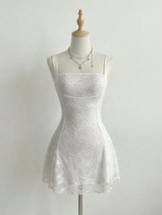 White lace dress on a mannequin with a silver star charm necklace