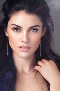 Woman with long dark hair wearing a necklace and earrings